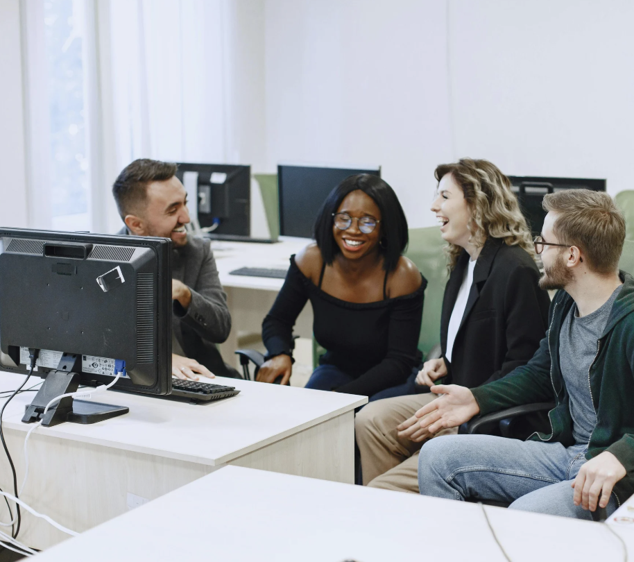 People gathered around a desktop computer smiling.